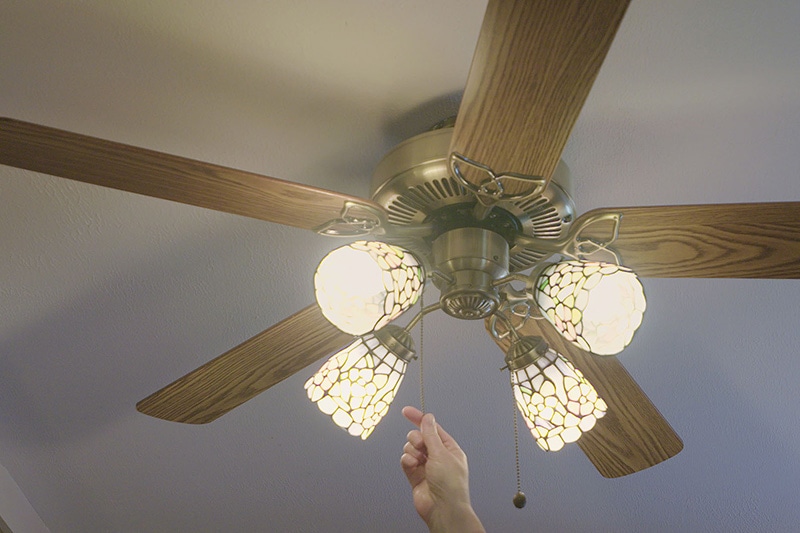 A ceiling fan being turned on with four lights | Energy Saving Tip 2