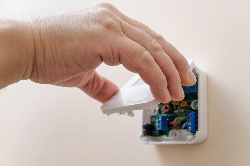 Image of someone fiddling with their thermostat. Tips to Troubleshoot Your Thermostat.