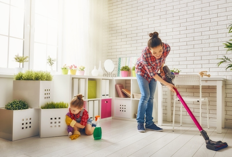 Happy family cleans the room. Mother and daughter do the cleaning in the house. A young woman and a little child girl wiped the dust and vacuumed the floor.